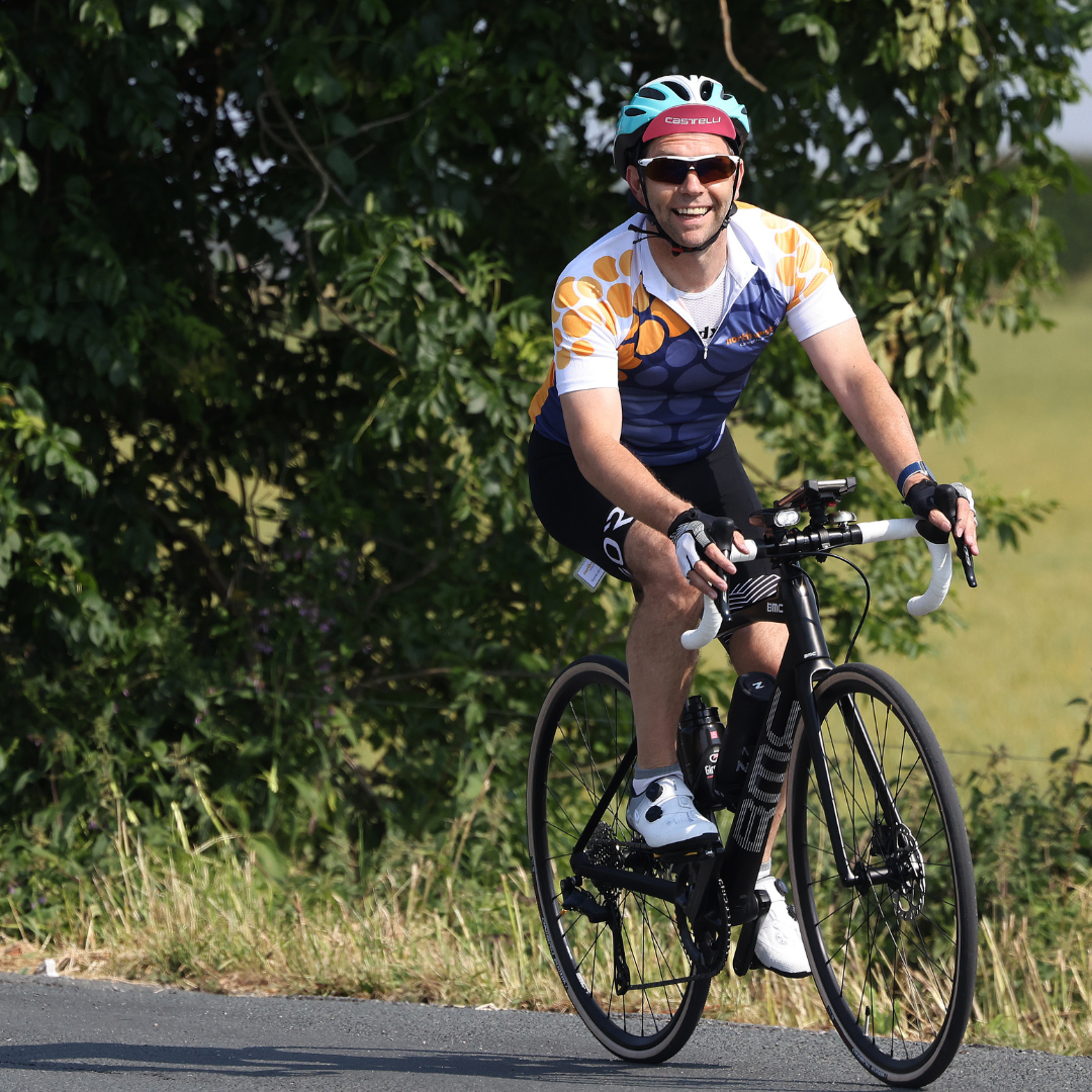 man smiling on bike cycling through countryside)